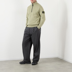 Model wearing Stone Island Compass Logo Half-Zip Fleece Sweatshirt in Laurel Green with dark wide-leg trousers and black shoes.