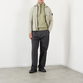 Model wearing Stone Island Compass Logo Half-Zip Fleece Sweatshirt in Laurel Green, styled with a light zip jacket, grey trousers and black shoes.