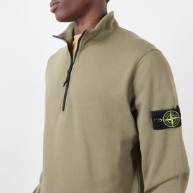 Model wearing Stone Island military green cotton half-zip sweatshirt with signature compass badge on sleeve