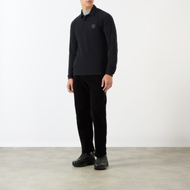 Model wearing Stone Island Compass Logo Long-Sleeved Polo Shirt in blue with black trousers and chunky trainers.