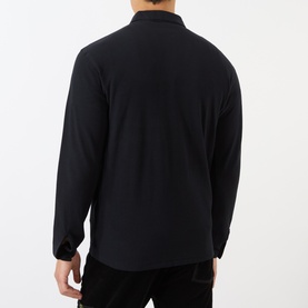 Model wearing Stone Island Compass Logo Long-Sleeved Polo Shirt in blue, rear view showing straight hemline and long sleeves.