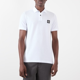 Model wearing Stone Island white polo shirt with signature badge patch, short sleeves and three-button placket, styled with grey trousers
