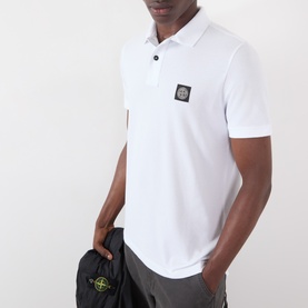 Model wearing Stone Island white polo shirt with signature compass badge patch, short sleeves, and two-button placket.