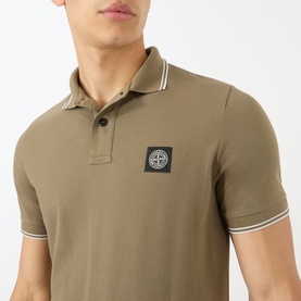 Model wearing Stone Island Compass Logo Tipped Polo Shirt in military green with white tipped collar and sleeve trims, chest badge logo.