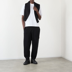 Model wearing Stone Island black cotton sweatpants, styled with a black gilet, white T-shirt and black lace-up shoes.