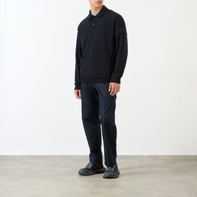 Model wearing a navy long-sleeve polo knit sweater, styled with dark navy trousers and grey chunky trainers