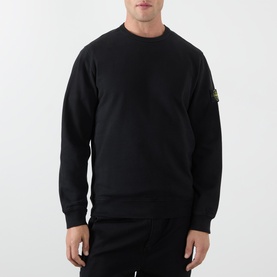Model wearing Stone Island black cotton crew neck sweatshirt with signature arm badge, paired with black trousers.