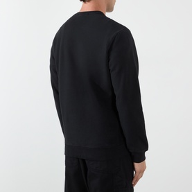 Model wearing Stone Island black cotton sweatshirt, rear view, styled with black cargo trousers.