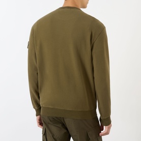 Model wearing Stone Island Compass Logo Badge Sweatshirt in green, crew neck, logo badge on sleeve, styled with khaki cargo trousers.