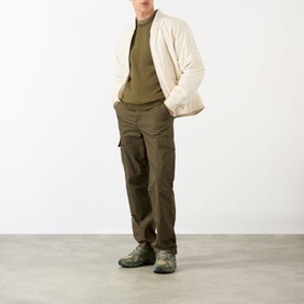 Model wearing Stone Island green Compass Logo Badge Sweatshirt, styled with cream jacket, dark cargo trousers and grey trainers.