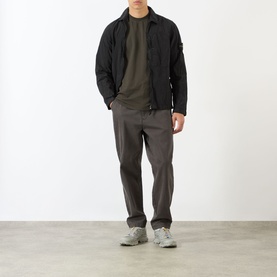 Model wearing Stone Island Compass Logo T-Shirt in coal grey, styled with black zip jacket, dark trousers and grey trainers.