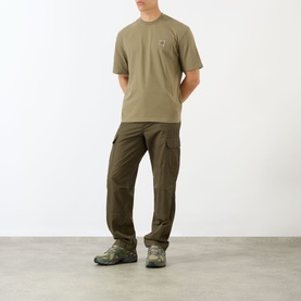 Model wearing Stone Island Compass Logo T-Shirt in military green with crew neck, styled with dark olive cargo trousers and trail trainers.