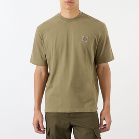 Model wearing Stone Island Compass Logo T-Shirt in military green, crew neck, short sleeves, with logo patch detail, styled with cargo trousers.