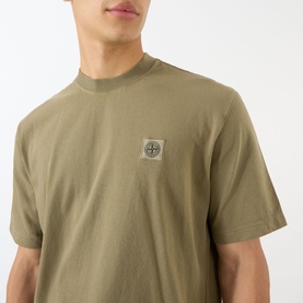 Model wearing Stone Island Compass Logo T-Shirt in military green, featuring crew neck and chest logo patch.