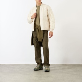 Model wearing Stone Island Compass Logo T-Shirt in military green, styled with ecru quilted jacket, khaki trousers and hiking boots.