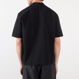 Model wearing Stone Island Compass Logo T-Shirt in black, rear view, round neck, short sleeves, styled with dark trousers.