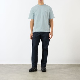 Model wearing Stone Island Compass Logo T-Shirt in ash grey with crew neck, styled with dark navy trousers and black trainers.