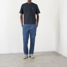 Model wearing Stone Island Compass Patch Logo T-Shirt in navy, styled with blue cargo trousers and grey trainers.
