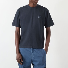 Model wearing Stone Island Compass Patch Logo T-Shirt in navy, crew neck, short sleeves, small chest logo patch, styled with blue jeans.