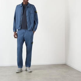 Model wearing Stone Island Compass Patch Logo T-Shirt in navy, styled with matching blue jacket and trousers, grey trainers.