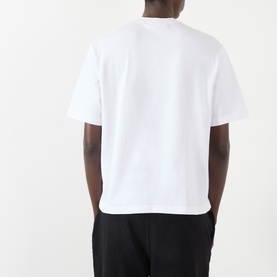 Model wearing Stone Island white cotton T-shirt, back view, with black trousers.