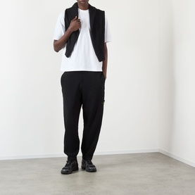 Model wearing Stone Island white cotton T-shirt with black gilet, black cargo trousers and black boots.