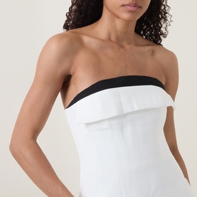 Model wearing Bardot orchid white strapless dress with black contrast trim and ruffle detail at bust, cropped close-up view
