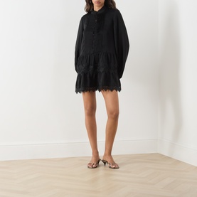 Model wearing Bardot Antonia Lace Trim Mini Dress in black with lace hem, pintuck detail and voluminous sleeves, styled with nude heeled mules.