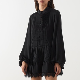 Model wearing Bardot Antonia Lace Trim Mini Dress in black with pintuck detail, voluminous sleeves, lace inserts and flared mini skirt.