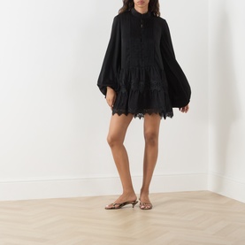 Model wearing Bardot Antonia Lace Trim Mini Dress in black with voluminous sleeves, lace inserts and flared skirt, styled with gold heeled sandals.