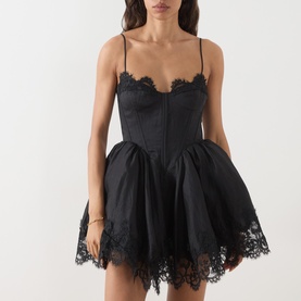 Model wearing Bardot black mini dress with corset bodice, spaghetti straps, lace trim detailing and full skirt