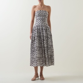 Model wearing Bardot Isalia Strapless Printed Dress in brown zebra print, midi length with box pleat skirt, styled with nude heeled sandals