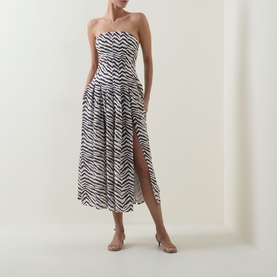 Model wearing Bardot Isalia Strapless Printed Dress in brown zebra print, midi length with box pleat skirt and left-leg split, styled with nude heels