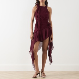 Model wearing Bardot Ivana Textured Mini Dress in deep plum with circle-cut ruffles, high-low hem and racer neckline, styled with black heeled