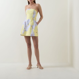 Model wearing yellow strapless mini dress with lilac floral print, styled with nude strappy heeled mules