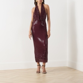 Model wearing Bardot deep plum sequin halterneck midi dress with wrap-style plunge neckline, styled with black strappy heels