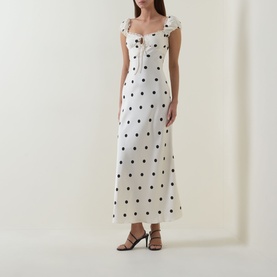 Model wearing Bardot black spot midi dress with square neckline, cap sleeves, button front detail, and fitted silhouette in white viscose fabric