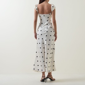 Model wearing Bardot black spot dress, rear view, showing square neckline, cap sleeves and midi length, styled with black heeled sandals