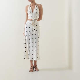 Model wearing Bardot Taryn Lace Detail Dress in canary yellow with black polka dots, halter neck, cut-out waist, midi length, styled with black