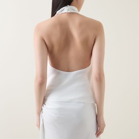 Model wearing Bardot Solene Draped Blouse in Orchid White, showing open back with high cowl neck and sleeveless design, styled with white skirt.