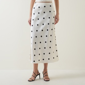 Model wearing Bardot Pheobe Polka Dot Slip Skirt in black spot, midi-length bias-cut satin with black heeled sandals