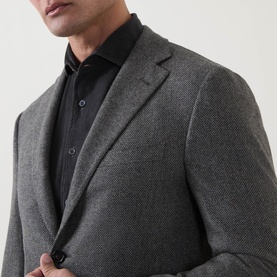 Model wearing Corneliani grey green virgin wool blazer jacket, styled with a black shirt, close-up detail view