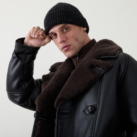 Model with Inis Meain Rib-Knit Beanie Hat in Black Fleck cashmere, ribbed construction, styled with black shearling coat