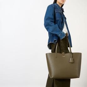 Model carrying Lauren Reversible Medium Tote in Botanic Green, grained finish, gold-toned hardware, worn over shoulder, styled with denim jacket
