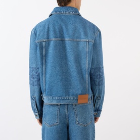 Model wearing Loewe Anagram Logo Denim Jacket in jeans blue, back view, with matching denim trousers. Logo badge detail visible.