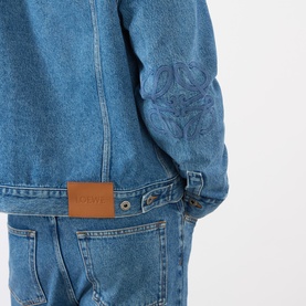 Model wearing Loewe Anagram Logo Denim Jacket in jeans blue, showing tonal Anagram elbow detail, logo badge and mid-wash finish.