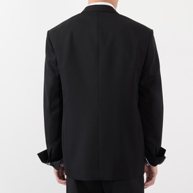 Model wearing Loewe black wool casual jacket, back view, with white shirt collar and cufflinks visible at wrists