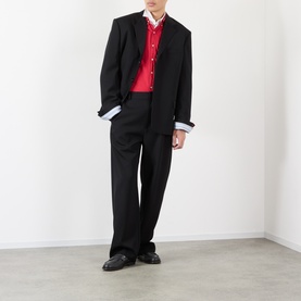 Model wearing Loewe black wool casual jacket with red polo, blue shirt, and black trousers and loafers
