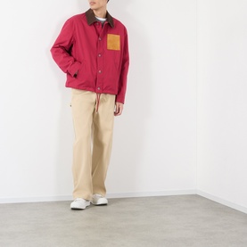 Model wearing Loewe red cotton casual jacket with tan chest pocket and collar, styled with beige trousers and white trainers