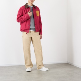 Model wearing Loewe red cotton casual jacket with brown collar and mustard chest pocket, styled with grey sweatshirt and beige trousers